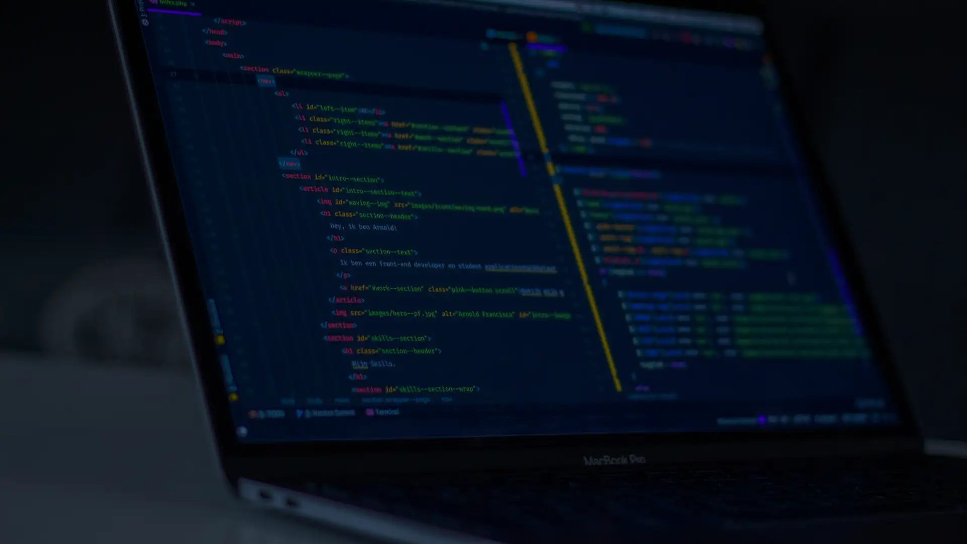 Portátil abierto con un editor de código iluminado en una habitación a oscuras